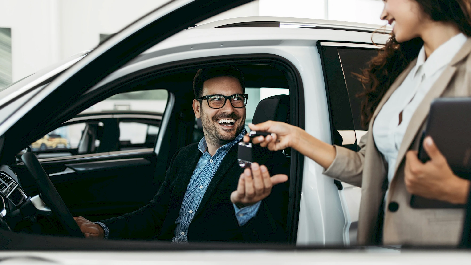 Nő átadja a kulcsot egy gépjárműben ülő férfinak