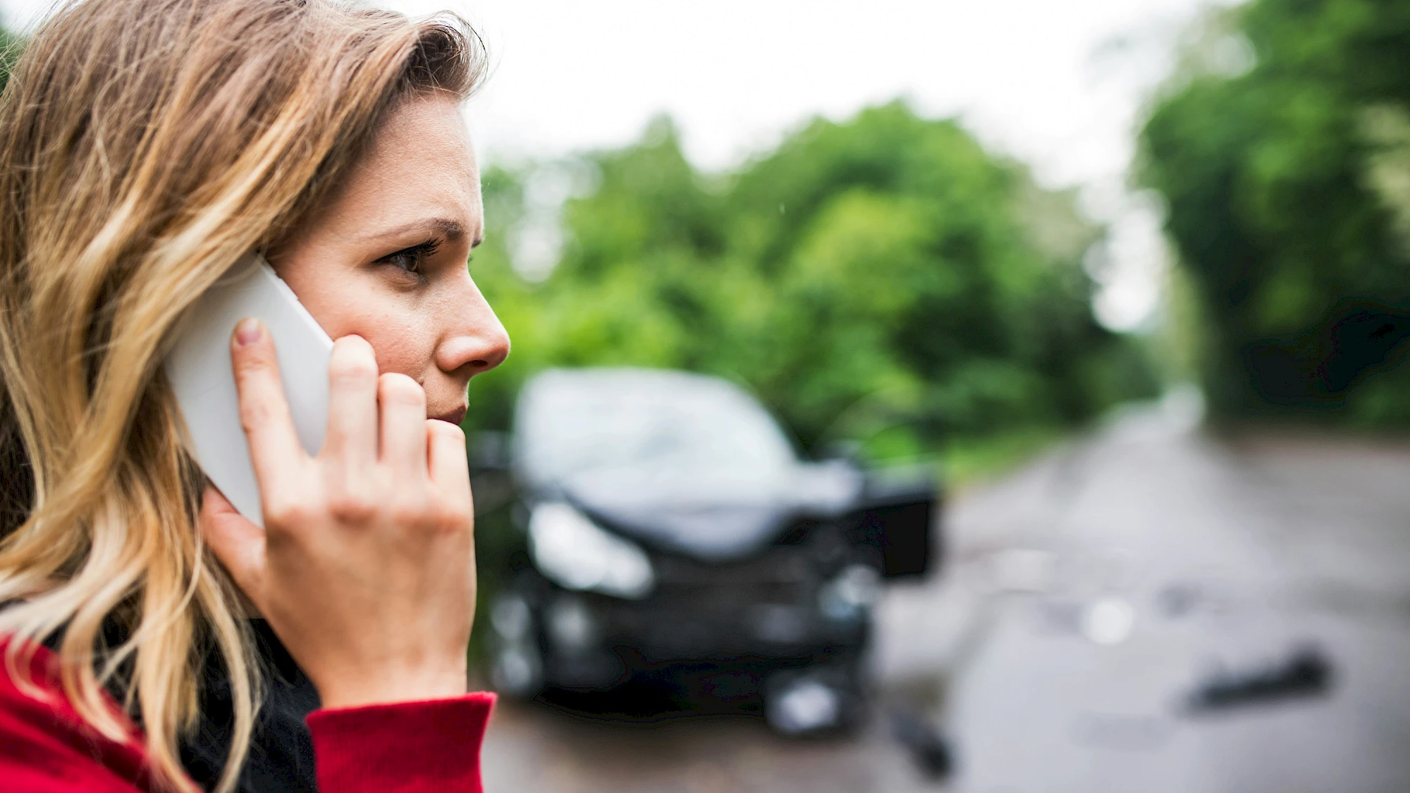 Nő telefonál a törött autó előtt