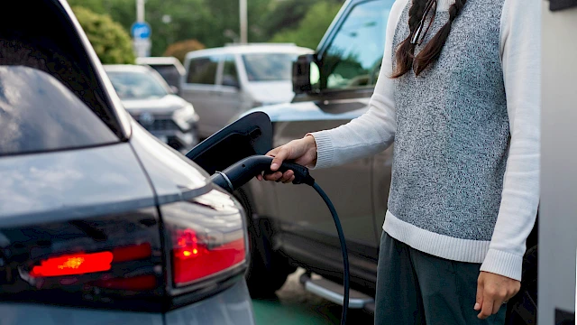 Nő töltőre helyez egy elektromos autót