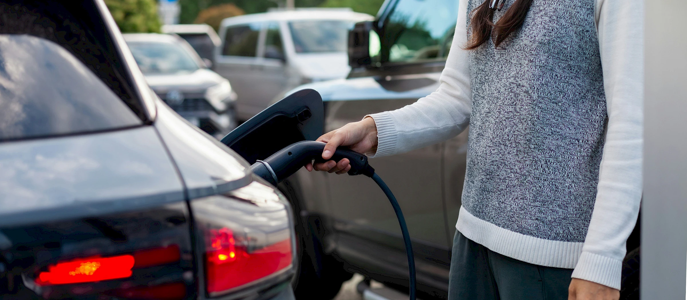 Nő töltőre helyez egy elektromos autót