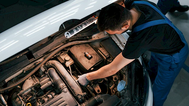 Autószerelő személyautó utasterét vizsgálja